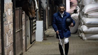 Fotoğrafta, görme engelli Tolga Dokuyucu, atların katıldığı yerde ve elinde beyaz baston var.