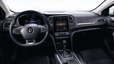 Fotoğrafta bir otomobilin içerisi görüntülenmiş. Renault marka logosu otomobilin direksiyonun ortasında yer alıyor. Aynı zamanda otomobilin birçok noktasında siyah renkler hakim.