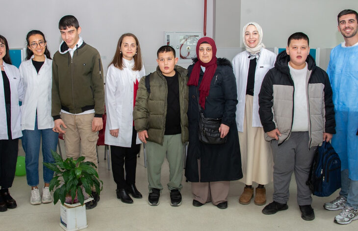 Fotoğrafta, engelli bireyler ve Selçuk Üniversitesi'nin diş hekimleri birlikte yan yana duruyorlar.