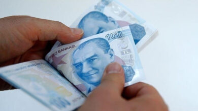 Görselde bir kişi elinde 100 TL banknotları tutuyor ve sayıyor. Banknotların üzerinde Mustafa Kemal Atatürk’ün portresi bulunuyor. Arka plan sade ve beyaz tonlarda. Görüntü, finansal bir işlemi veya ödeme sürecini çağrıştırıyor.
