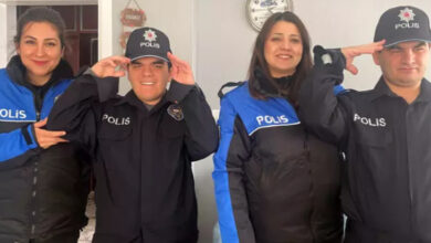 Görselde, iki genç erkek ve iki kadın polis memuru birlikte poz veriyor. Gençler, polis üniforması giymiş ve şapka takmış, gururla selam veriyorlar. Kadın polis memurları ise onlarla birlikte gülümseyerek poz veriyor. Arka planda duvarda bir saat ve “Sabır” yazılı küçük bir dekor bulunuyor.