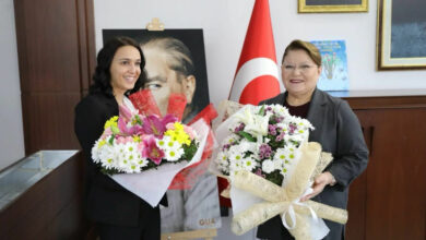 Didim Belediye Başkanı Hatice Gençay ve Basın Yayın ve Halkla İlişkiler Müdürlüğü görevine getirilen Fatma Duran ellerinde çiçeklerle kameraya doğru bakarak gülümsüyorlar.