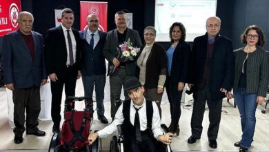 Bu fotoğrafta, "Engelli Hakları ve Erişilebilirlik" konulu söyleşiye katılan bir grup insan görülüyor. Etkinlik, Yalova Aile ve Sosyal Hizmetler İl Müdürlüğü ve Yeni Yaşam Engelliler Derneği iş birliğiyle Engelsiz Kafe Konferans Salonu'nda düzenlenmiş. Katılımcılar arasında takım elbiseli yetkililer, sivil toplum temsilcileri ve engelli bireyler bulunuyor. Ön planda ise şapkalı bir birey tekerlekli sandalyesiyle poz veriyor.