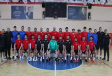 Görselde, kırmızı ve siyah formalar giymiş bir grup erkek sporcu ve teknik ekip, bir spor salonunda toplu halde poz veriyor. İşitme Engelli Erkek Futsal Milli Takımı’nın, Sırbistan'daki Avrupa Şampiyonası eleme maçları için Aksaray'da yaptığı hazırlıkları yansıtan bir kare.
