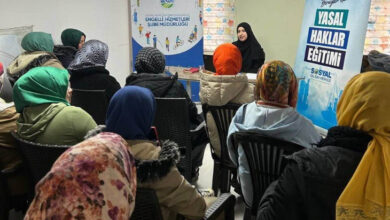 Görselde, bir eğitim seminerinde kadın katılımcıların uzman bir konuşmacıyı dinlediği görülüyor. Arka planda "Engelli Hizmetleri Şube Müdürlüğü" ve "Yasal Haklar Eğitimi" yazılı afişler bulunuyor. Katılımcılar başörtülü ve kışlık kıyafetler giymiş, sandalyelerde düzenli bir şekilde oturuyorlar. Konuşmacı, siyah kıyafetler içinde masanın başında oturarak bir şeyler anlatıyor.