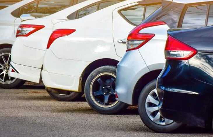 Fotoğrafta, bir otoparkta arka arkaya park edilmiş farklı renklerde otomobiller görülüyor. Araçların arka kısımları ve far detayları dikkat çekiyor. Beyaz, gümüş ve siyah renklerdeki araçlar, modern tasarıma sahip.