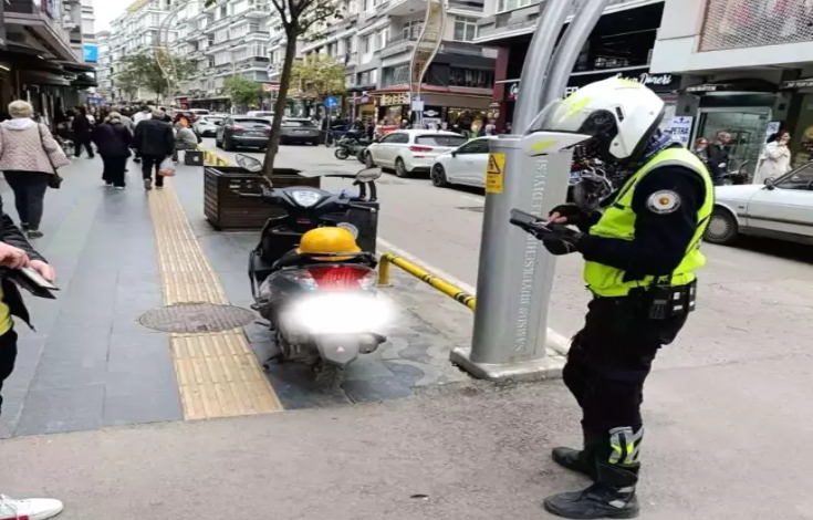 Memur motosikletin yanında cezai işlem uyguluyor.