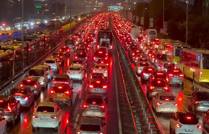 Trafik yoğunluğu olan yolda araçlar kırmızı sinyal vererek ilerliyor.