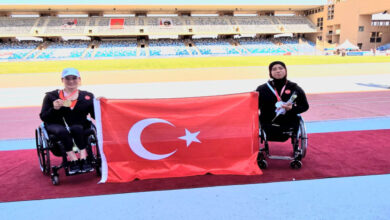 Hamide Doğangün ile Zübeyde Süpürgeci, Türk Bayrağı tutarak poz veriyor.