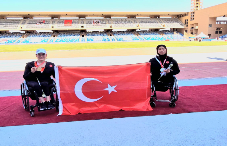 Hamide Doğangün ile Zübeyde Süpürgeci, Türk Bayrağı tutarak poz veriyor.