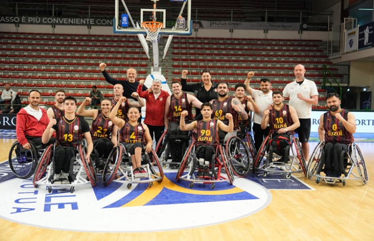 Galatasaray Fuzul Tekerlekli Sandalye Basketbol Takımı ve teknik heyet kol kaslarını sıkarak güç pozu veriyor.