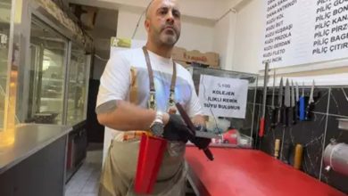 Görselde, bir kasap dükkânında çalışan bir adam yer alıyor. Üzerinde önlük, belinde çeşitli bıçaklar ve bir et zımbası taşıyor. Arka planda et ürünlerinin yazılı olduğu fiyat listesi ve çeşitli bıçaklar duvara dizilmiş halde görülüyor. Kırmızı tezgâhın yanında, cam kutuda “%100 Kolajen İlikli Kemik Suyu Bulunur” yazısı dikkat çekiyor.