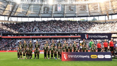 Bu görselde, Trendyol Süper Lig kapsamında oynanan Beşiktaş – Adana Demirspor maçından önceki seremoni anı görülmektedir. Beşiktaş futbolcuları ve minik taraftarlar, tribünler önünde dizilmiş halde durmaktadır. Stadyum tamamen doludur ve Beşiktaş logosu arka planda net şekilde görülmektedir. Görselde dikkat çeken detaylardan biri, Engelliler Haftası kapsamında sahaya çıkan üç engelli bireyin futbolcularla birlikte yer almasıdır.