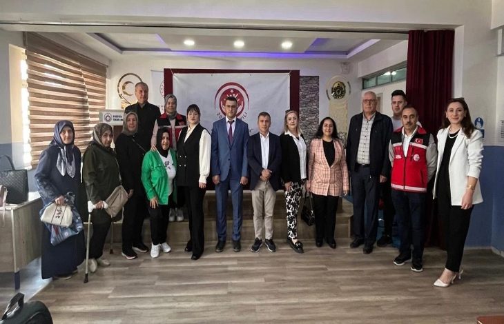 Farklı yaş gruplarından oluşan kadın ve erkekler ayakta bir şekilde fotoğrafta yer alıyor.