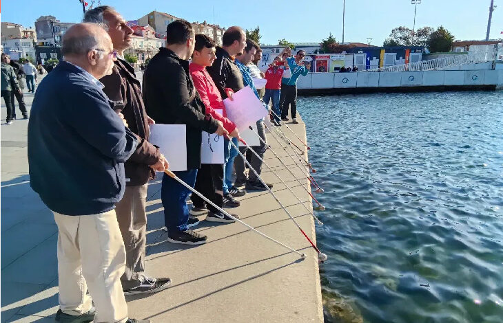 Bu fotoğrafta, beyaz baston kullanan bir grup görme engelli birey deniz kenarında yan yana duruyor. Ellerinde pankartlar var ve suya oldukça yakın bir noktadalar. Görsel, erişilebilirlik sorunlarına dikkat çeken bir farkındalık etkinliğini yansıtıyor.