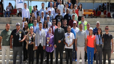 Bu görselde, Hatay Büyükşehir Belediyesi’nin Engelliler Haftası kapsamında düzenlediği bir etkinlikte bir araya gelen kalabalık bir grup yer alıyor. Katılımcılar açık alanda, tribün önünde toplu halde poz veriyor. Ön sırada bazı kişilerin ellerinde ödül kupaları ve madalyalar var; bu da etkinlik kapsamında yarışmalar ya da ödüllü faaliyetler düzenlendiğini gösteriyor. Farklı yaş ve cinsiyetlerden bireylerin bir arada olması, kapsayıcılığı ve toplumsal dayanışmayı vurguluyor.