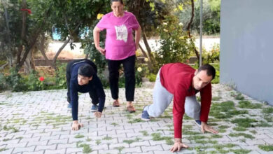 Fotoğrafta, yerde elleriyle destek alarak emekleyen iki engelli birey ve arkalarında anneleri yer alıyor.