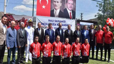 Bu görselde, İzmir'deki Karşıyaka Özel Eğitim Meslek Okulu’nda 10-16 Mayıs Engelliler Haftası kapsamında düzenlenen bir farkındalık etkinliği görülmektedir. Halı saha üzerinde gerçekleştirilen etkinlikte, ön sırada Türk bayraklı kırmızı formalar giymiş, amputee futbolcular diz çökmüş şekilde poz vermektedir. Arkalarında ise sivil ve askerî yetkililer ile öğretmenler olmak üzere çeşitli protokol üyeleri ayakta durmaktadır.