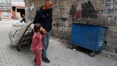 Görme engelli Ali Dağ arkasında geri dönüşüm arabasını sürüklüyor ve kızının elini tutarak çöp kutusunun önünde bulunuyor.