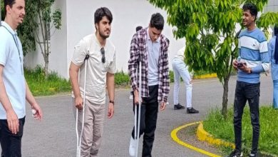 Fotoğrafta bir etkinlik kapsamında koltuk değneği kullanarak yürümeye çalışan üniversite öğrencileri yer alıyor.