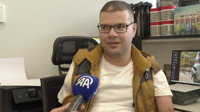 Sağ kolu ampute olan Yusuf İslamoğlu fotoğrafta yer alıyor. İslamoğlu'nun önünde Anadolu Ajansı’na ait bir mikrofon var.