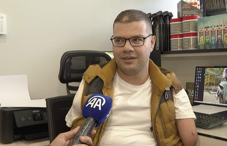 Sağ kolu ampute olan Yusuf İslamoğlu fotoğrafta yer alıyor. İslamoğlu'nun önünde Anadolu Ajansı’na ait bir mikrofon var.