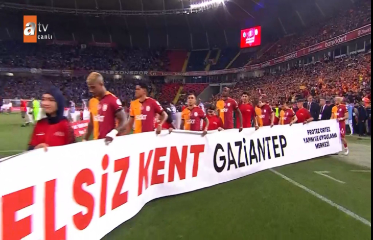 Engelsiz Kent Gaziantep yazılı pankartı tutan Galatasaraylı futbolcular ve engelliler sahaya çıkıyor.