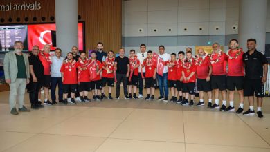 Milli Takım oyuncuları ve yöneticiler havaalanında fotoğraf çektiriyor.