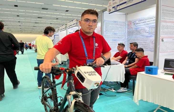 Muhammed Emir Ünalan, yapay zeka destekli bisikleti tutarak poz veriyor.