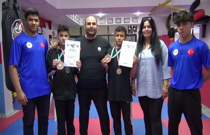 Fotoğrafta görme engelli sporcular ve antrenörleri müsabakalardan elde edilen madalyaları ile başarı belgelerini kameraya doğru gösteriyorlar.