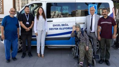 Görselde, Yunus Emre Belediyesi'ne ait olduğu düşünülen transport tipi bir aracın önünde, akülü tekerlekli sandalye kullanan yaşlı bir kadın ile belediye yetkilileri yer alıyor.