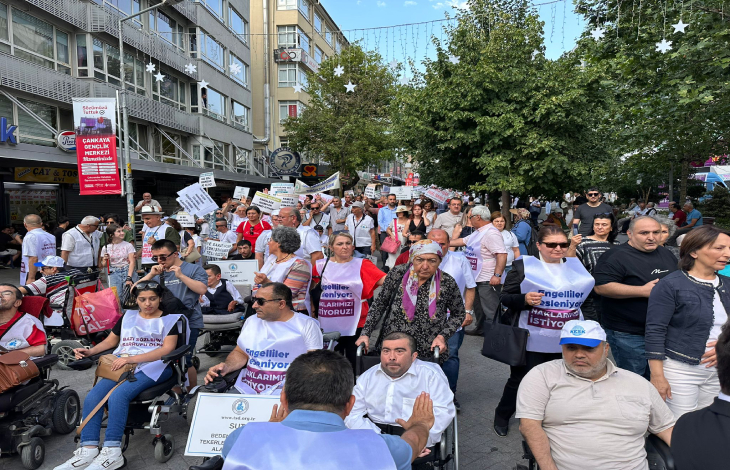 En önde bedensel engelliler ile arkalarında döviz tutan yoğun kitle yürüyüş yapıyor.