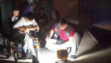 Bu görselde, gece vakti dış mekânda gerçekleşen bir olayın ardından bir polis memuru, tekerlekli sandalyedeki bir bireyden ifade alıyor. Aydınlatma taşınabilir bir ışıkla sağlanmış ve sahneye yoğun bir ışık tutulmuş. Polis memuru yerde diz çökerek not alırken, engelli birey olayla ilgili bilgi veriyor. Arka planda başka kişiler de bulunuyor.