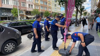 Görselde, Çorum Belediyesi Zabıta Müdürlüğü ekipleri bir kaldırımda denetim yapıyor. Zabıta ekipleri, sarı kılavuz çizgilerin yani görme engelli yolunun üzerine yerleştirilmiş bir tanıtım afişini kaldırıyor. Bu afişin görme engelliler için yapılmış yürüyüş yolunu kapattığı görülüyor. Arka planda apartmanlar, dükkânlar ve park etmiş araçlar yer almakta.