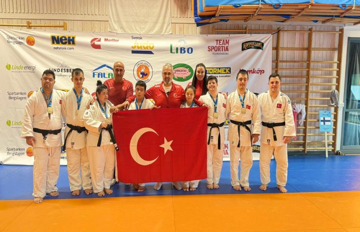 Down Judo Milli Takımı ile teknik kadro Türk Bayrağı tutarak poz veriyor.