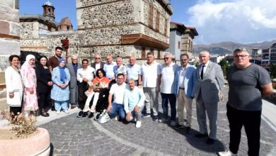 Görselde, kalabalık bir grup insan, ay benzeri bir şekilde yan yana dizilerek toplu bir fotoğraf çekimi gerçekleştiriyor. Grubun içerisinde akülü tekerlekli sandalye kullanan engelli bir kadın ve koltuk değneğiyle yanında ayakta duran engelli bir adam yer alıyor.