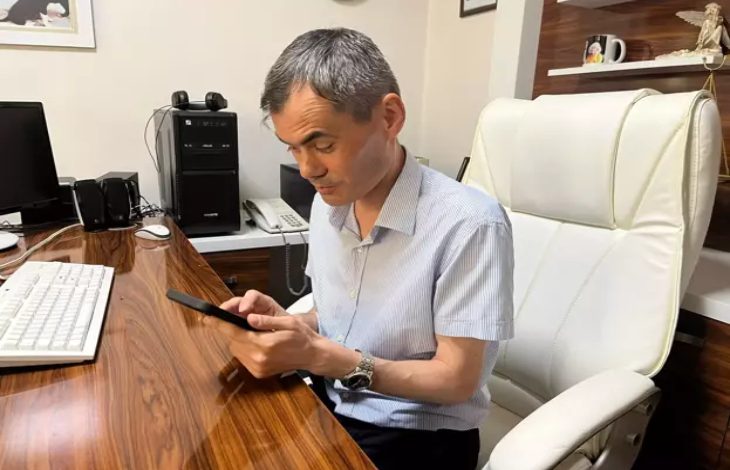 Görme engelli Avukat Bünyamin Gürsaçtı ofis masasında telefon kullanıyor.