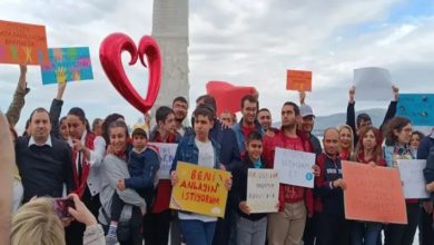 Görselde, ellerinde pankartlar taşıyan bir grup insan açık alanda toplanmış. Pankartlarda otizmli bireylerin anlaşılması, istihdam hakları ve farkındalık taleplerine dair ifadeler yer alıyor. Kalabalık, toplumsal farkındalık ve hak arayışı amacıyla bir araya gelmiş. Arka planda büyük bir kalp figürü ve Türk bayrağı da görülüyor.