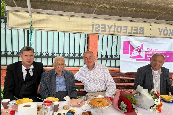 Görselde, Prof. Dr. Coşkun Özdemir ve orta yaşlarda olduğu düşünülen üç erkek daha yer alıyor. Önlerinde doğum günü kutlamasından kalan pasta ve çeşitli yiyecekler olduğu görünmektedir.