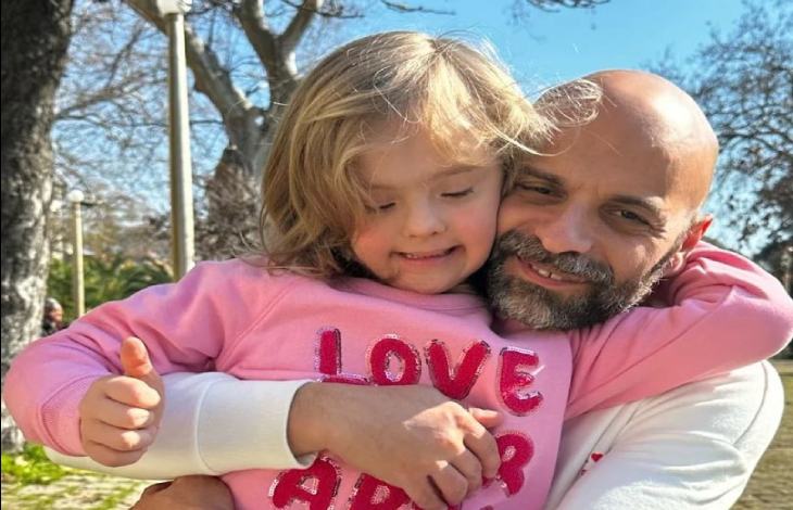 Luca Tranapese, pembe kazaklı down sendromlu çocuğu Alba'ya iki koluyla sarılıyor.