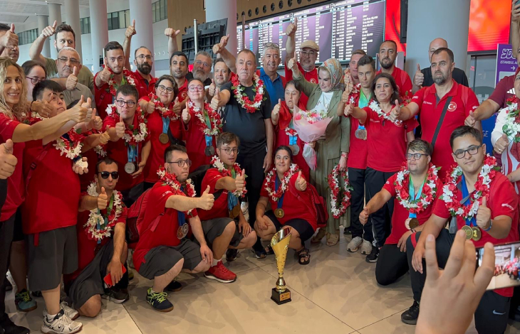 Türkiye Özel Sporcular Spor Federasyonu yönetimi ile Özel Sporcular baş parmaklarını kaldırarak kupa önünde poz veriyor.