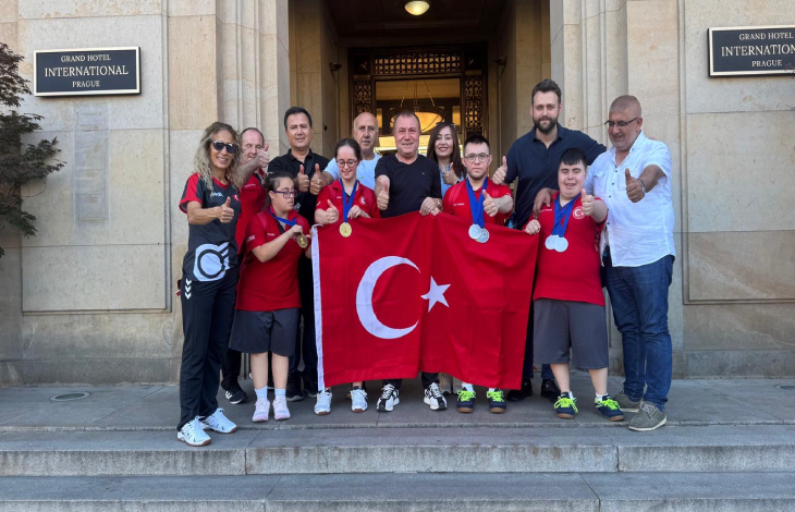 Başkan Birol Aydın ile Avrupa Şampiyonasına katılan özel sporcular Türk bayrağı tutarak poz veriyor.