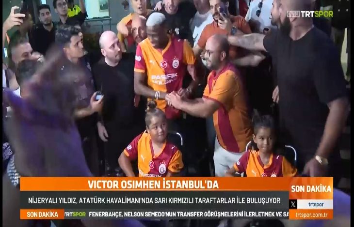 Görselde, Galatasaray’ın yeni transferi Nijeryalı futbolcu Victor Osimhen, Atatürk Havalimanı’nda sarı-kırmızılı taraftarlar tarafından coşkuyla karşılanıyor. Osimhen Galatasaray formasıyla ortada yer alırken, etrafı taraftarlarla çevrili. Kalabalığın içinde dikkat çeken detaylardan biri de, Galatasaray forması giymiş iki engelli kız çocuğunun tekerlekli sandalyede ön sırada yer alması.
