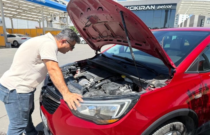 Görselde, Abdullah Aktaş Opel Crossland X SUV marka bir araç başında ön kaputu açmış ve aracın motor bölümünü inceliyor.