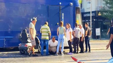 Kazanın olduğu alanda tramvay ve akülü aracın yanında yerde oturan engelli sürücünün başında vatandaşlar bulunuyor.