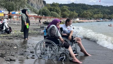 Bolu Belediyesi’nin düzenlediği etkinlik sayesinde hayatında ilk kez denizi gören 76 yaşındaki Huriye Çelik, sahilde mutluluğun tadını çıkarıyor. Bir sahil kenarında çekilmiş bu fotoğrafta, tekerlekli sandalyedeki yaşlı bir kadın ve yanındaki genç kadın birlikte deniz kıyısında oturuyor. Kadının ayağına dalgalar çarpıyor, yüzünde ise neşe dolu bir gülümseme var. Arka planda başka tekerlekli sandalye kullanıcıları ve onları izleyen insanlar görülüyor.
