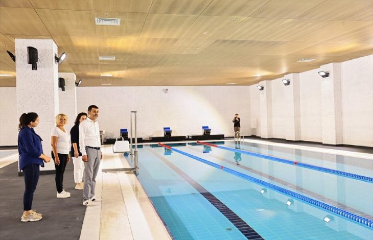 Denizli Büyükşehir Belediye Başkanı Bülent Nuri Çavuşoğlu ve kendisine bilgi veren yöneticiler yüzme salonunda havuzu inceliyor.