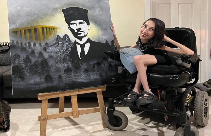 Tekerlekli sandalyesinde poz veren Gülçin Sipahi’nin yanında bulunan paletteki eserinde Atatürk, Anıtkabir, kurt figürü ve sisler arasındaki orman detayları yer alıyor.