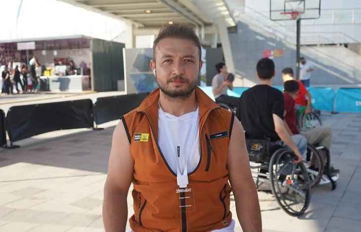 Görselde tekerlekli sandalye basketbol takımı oyuncusu Osman Yüksel, bir basketbol sahasında röportaj gerçekleştirirken görülmektedir.