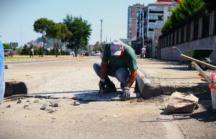 Erkek personel kaldırım taşlarını rampa alanına döşüyor.